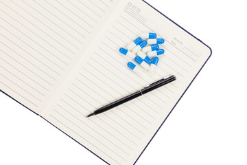 Naklejka premium Medicine capsules on notebook with pen for pharmaceutical research and laboratory documentation