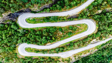 Captivating view of a winding road nestled amidst vibrant green foliage in Fortun, Norway. The road offers a thrilling journey through the breathtaking Norwegian landscape, ideal for exploration.