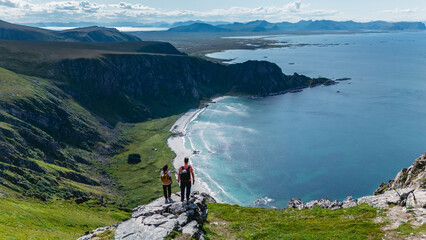 Vibrant landscape captures adventurous hikers standing atop Matind Mountain, overlooking the...