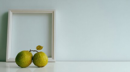 Two yellow-green fruits beside a white frame on a light background