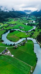 Foto auf Acrylglas Grün Lush greenery blankets the landscape of Stryn in Norway, with rivers gracefully winding through the valley. Quaint farmhouses dot the terrain under the soft light of an overcast sky.  © Fokke Baarssen