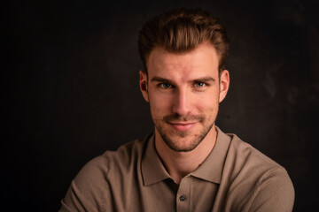 Headshot of a handsome young man against isolated dark background