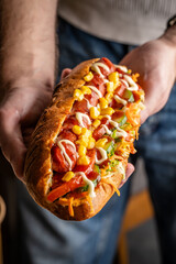Hot dog with vegetables, corn, and sauces