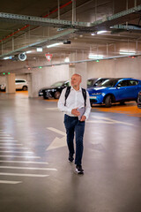 Fototapeta premium Full length of a senior male commuter walking in the car park towards the exit