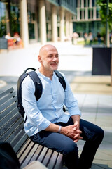 Confident middle aged man sitting on a bench in a city street