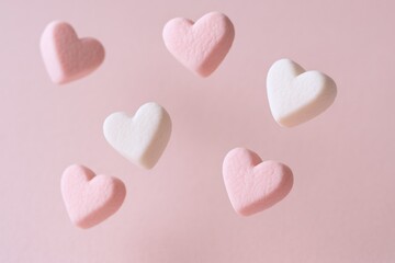 Fototapeta premium Sweet Pink and White Heart Candies Scattered on a Pink Background for Valentine's Day