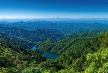 Obraz premium Serene view of verdant, rolling mountains with a calm lake nestled among them under a clear blue sky offering a sense of peaceful isolation