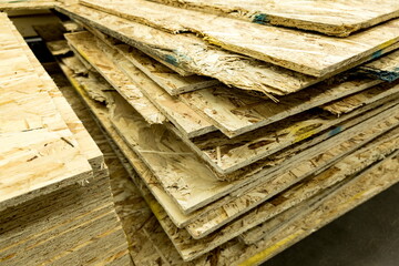 Stacked layers of oriented strand board in a storage area for construction materials during daylight