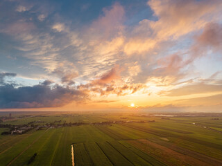 Aerial view of rural farmland under a colorful sunset sky in the Netherlands.
