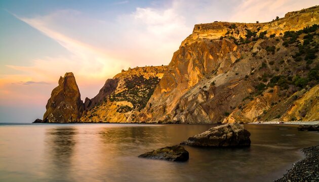 Dramatic coastal scenery at sunset, featuring rugged, multicolored cliffs meeting a tranquil, reflective sea.