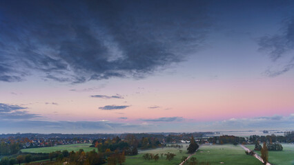 Breathtaking balcony view overlooking the lush green fields of Holland's countryside during a misty summer sunrise near Amsterdam, Netherlands