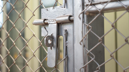 Close-up at metal door bolt on the fence wire gate, it using to secure the gate during it closed. Building equipment object, selective focus.