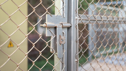 Close-up at metal door bolt on the fence wire gate, it using to secure the gate during it closed. Building equipment object, selective focus.