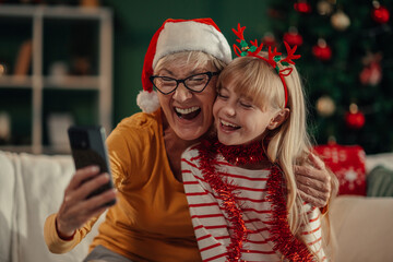 Grandmother and granddaughter making a video call wearing christmas costumes