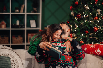 Happy couple embracing after exchanging christmas gifts at home