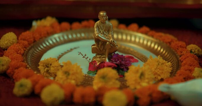 Devotees performing Sai Baba&rsquo;s puja with a small brass idol, lighting lamps, and offering fresh flowers, creating a serene and devotional atmosphere filled with faith and positive energy