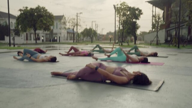 Group yoga session outdoors featuring the relaxing supine spinal twist for flexibility, core release, and spine health.