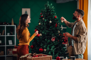 Couple decorating christmas tree at home together