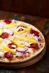 Pizza with chorizo ​​sausage, mozzarella cheese and yellow pepper. Rustic wooden background. Soft focus.	