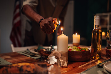 Chef lighting candles on table with american flag in background