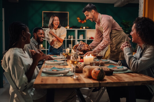 Friends celebrating thanksgiving enjoying roasted turkey together - Powered by Adobe