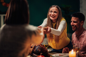 Happy friends sharing food, celebrating thanksgiving dinner together