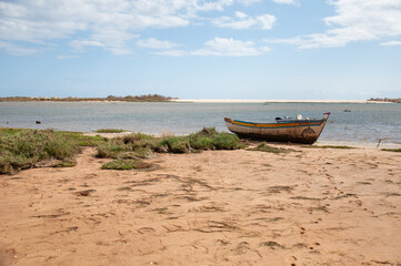 Obraz premium Cacela Beach, Algarve, Portugal with a traditional wooden fishing boat beached on a sandy shore