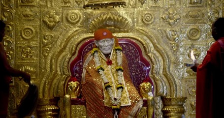 Sai Baba is seated peacefully in the temple, radiating a divine positive aura that fills the atmosphere with serenity and devotion