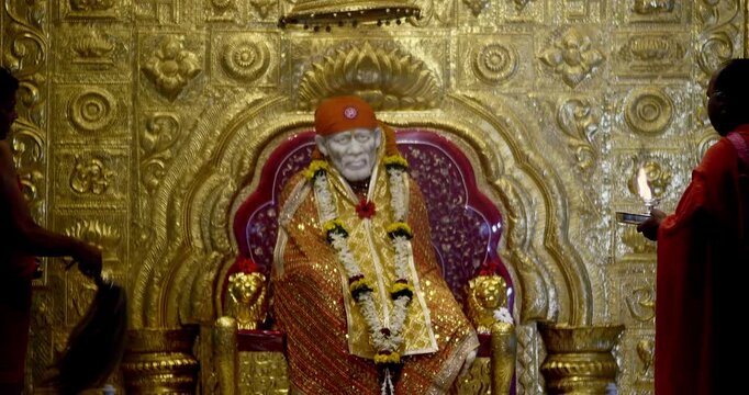 Sai Baba is seated peacefully in the temple, radiating a divine positive aura that fills the atmosphere with serenity and devotion