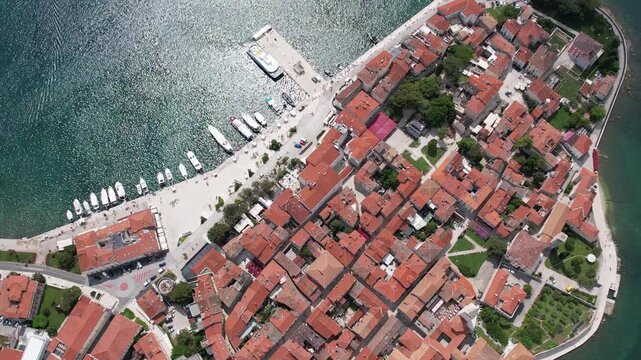 Aerial drone view of Porec Old Town and the Euphrasian Basilica on the Istrian coast of Croatia. The red-tiled roofs and historical buildings rest along the scenic Adriatic shoreline with marina.
