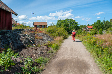 Unrecognizable woman walking at Harstena island in the Baltic Sea. This former fishing village in the Swedish archipelago of Gryt is now a popular tourist destination.