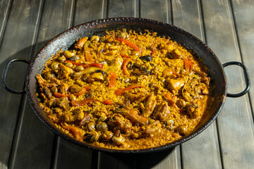 A large paella with lots of meat, rice, and vegetables.