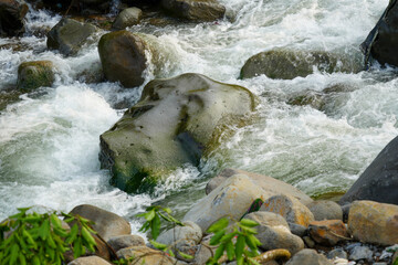 View of a fast flowing river over a collection of natural rocks and gravel.