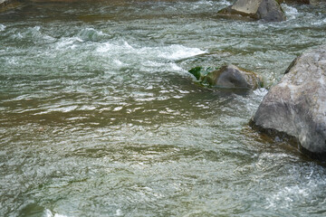 View of a fast flowing river over a collection of natural rocks and gravel.