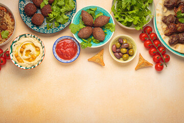 Border composition of middle eastern or Arab dishes and assorted meze on light beige background. Meat kebab, falafel, hummus, sambusak, rice, kibbeh, pita. Halal food. Lebanese cuisine, copy space