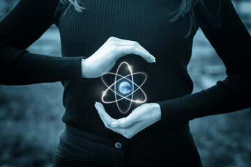 Creative hands hold glowing atom symbol with earth inside.