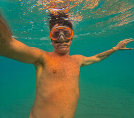 Fototapeta premium Man swims underwater in the Mediterranean Sea. The man is forty years old and of Caucasian origin 