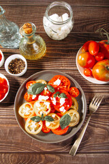 Sliced fresh tomato salad with basil leaves sprinkled with feta cheese