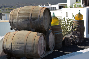 Obraz premium Barrels and big bottles with grape wine - malvasia. Bodega, Lanzarote, Spain
