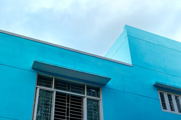 Bright blue modern building exterior with geometric lines and open window
