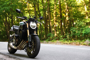 Obraz premium Modern black motorcycle parked on road outdoors. Space for text