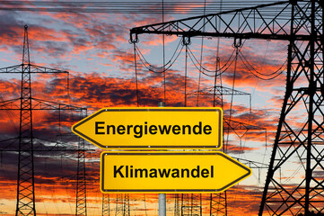 Obraz premium Vor vielen Strommasten einer Hochspannungsleitung steht ein Schild mit der Aufschrift Energiewende und Klimawandel - FOTOMONTAGE