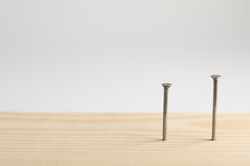 Metal nails in wooden plank on white background, closeup. Space for text