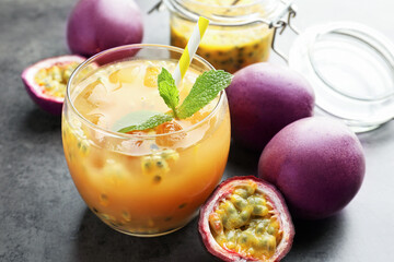 Tasty passion fruit drink with mint and fresh fruits on grey table, closeup