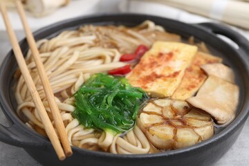 Tasty ramen with enoki and king oyster (eryngii) mushrooms on light grey table, closeup