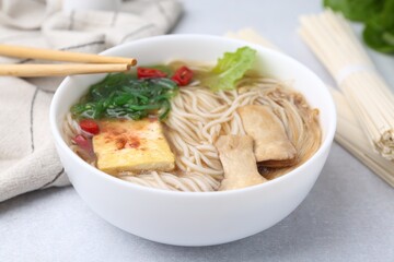 Tasty ramen with enoki and king oyster (eryngii) mushrooms on white table, closeup