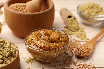 Different types of mustard on wooden table, closeup