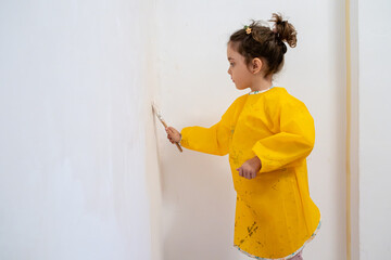 Little girl painting a room with focus and care