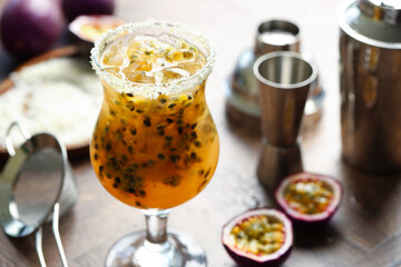 Tasty passion fruit drink in glass, fresh fruits and bartender's tools on table, closeup