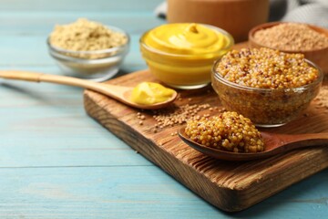 Different types of mustard on light blue wooden table, closeup